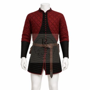 May include: A quilted red and black medieval doublet and tunic set. The red jacket has a diamond pattern and long sleeves with black cuffs. The tunic is black with a brown belt and pouches. The outfit is displayed on a mannequin.