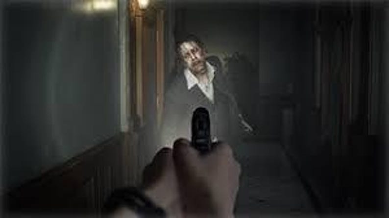 Puede incluir: Perspectiva en primera persona de una persona sosteniendo una pistola negra, apuntando a un zombi en un pasillo oscuro. El zombi lleva traje y corbata, con la cara p&aacute;lida y sangre. Escena de terror.