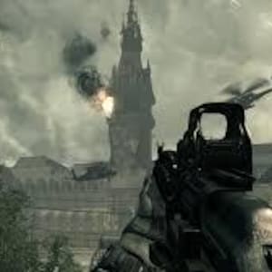 K&ouml;nnte beinhalten: Ego-Perspektive aus einem Videospiel, mit dem Visier einer Waffe auf ein entferntes Geb&auml;ude gerichtet. Hubschrauber und Flugzeuge sind am Himmel zu sehen, mit Explosionen und Rauch. Die Szene spielt in einer kriegszerst&ouml;rten Umgebung.