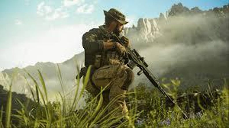 K&ouml;nnte beinhalten: Eine Person in Tarnkleidung, die einen Hut tr&auml;gt und ein Gewehr h&auml;lt. Die Person befindet sich in einer nat&uuml;rlichen Umgebung im Freien mit Bergen im Hintergrund. Das Bild konzentriert sich auf milit&auml;rische Ausr&uuml;stung und Outdoor-Aktivit&auml;ten.