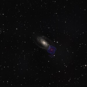 Può includere: Un'immagine dello spazio profondo che mostra una galassia a spirale con un nucleo luminoso e bracci vorticosi, accanto a una galassia più piccola e allungata. Lo sfondo scuro è pieno di numerose stelle, creando una scena cosmica.