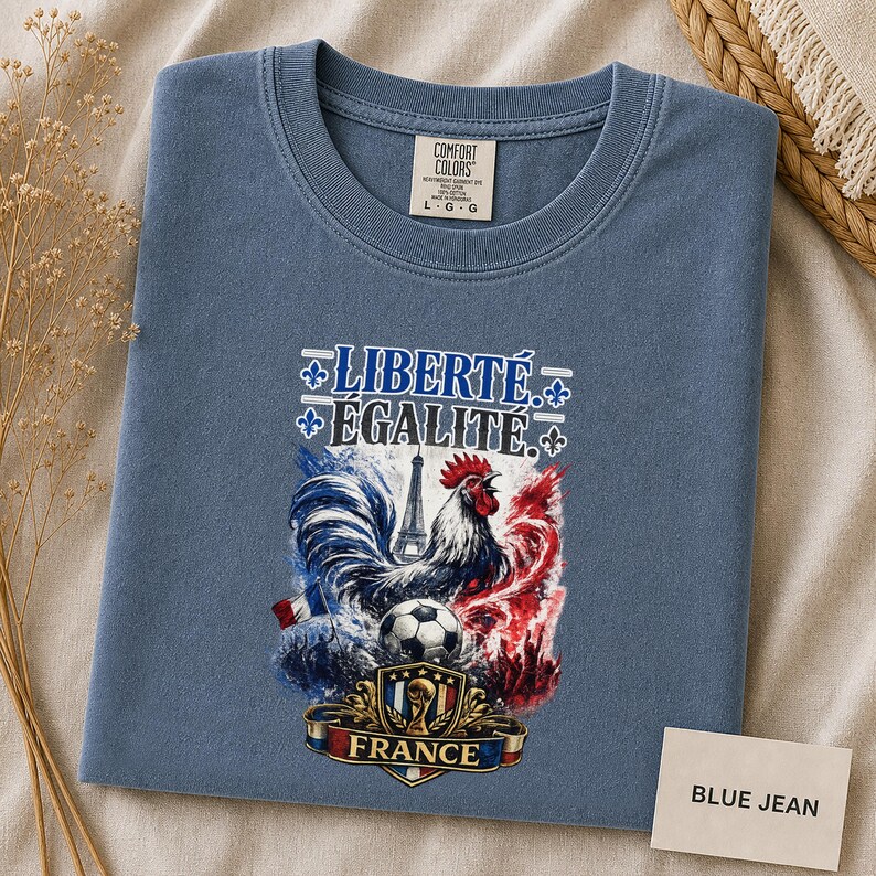 Puede incluir: Una camiseta de color azul jean con un estampado gr&aacute;fico que incluye el texto LIBERT&Eacute; &Eacute;GALIT&Eacute; y FRANCE. El dise&ntilde;o muestra un gallo, la Torre Eiffel, un bal&oacute;n de f&uacute;tbol y un escudo con detalles en acuarela de color rojo, blanco y azul.