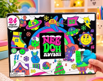 May include: A black Nee Doh Advent calendar box featuring colorful illustrations of a rainbow, roller skate, sun, and various numbers from 1 to 24. The box displays the text 24 days of surprises and Nee Doh Advent. A blue rubber duck toy is visible.