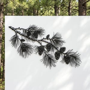 May include: A matte black metal wall art piece shaped like a pine branch with detailed needles and multiple pinecones. The design features a horizontal orientation with intricate cutouts that define the texture of the needles and the scales of the cones.