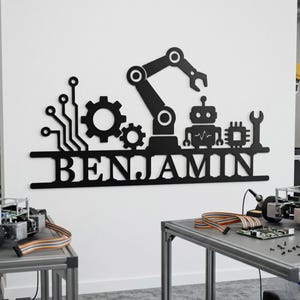 Puede incluir: Un letrero de pared negro con el nombre BENJAMIN en letras mayúsculas. Sobre el nombre hay siluetas de un brazo robótico, un pequeño robot, dos engranajes, un patrón de circuito, un chip de computadora y una llave inglesa, todo en negro.