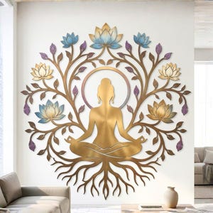 May include: A gold-toned metal wall art piece featuring a central silhouette of a figure in a seated meditation pose. The figure is surrounded by a circular halo and intricate, branching tree roots and stems adorned with blue and gold lotus flowers.