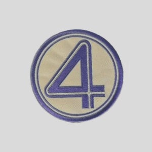 May include: Embroidered patch featuring a stylized number "4" in a bold, geometric design. The number is in a deep purple color, outlined in white, set against a tan background within a circular border. The border is a darker purple.