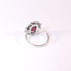 Puede incluir: Un anillo de plata con una piedra preciosa roja engastada en un delicado dise&ntilde;o de filigrana.