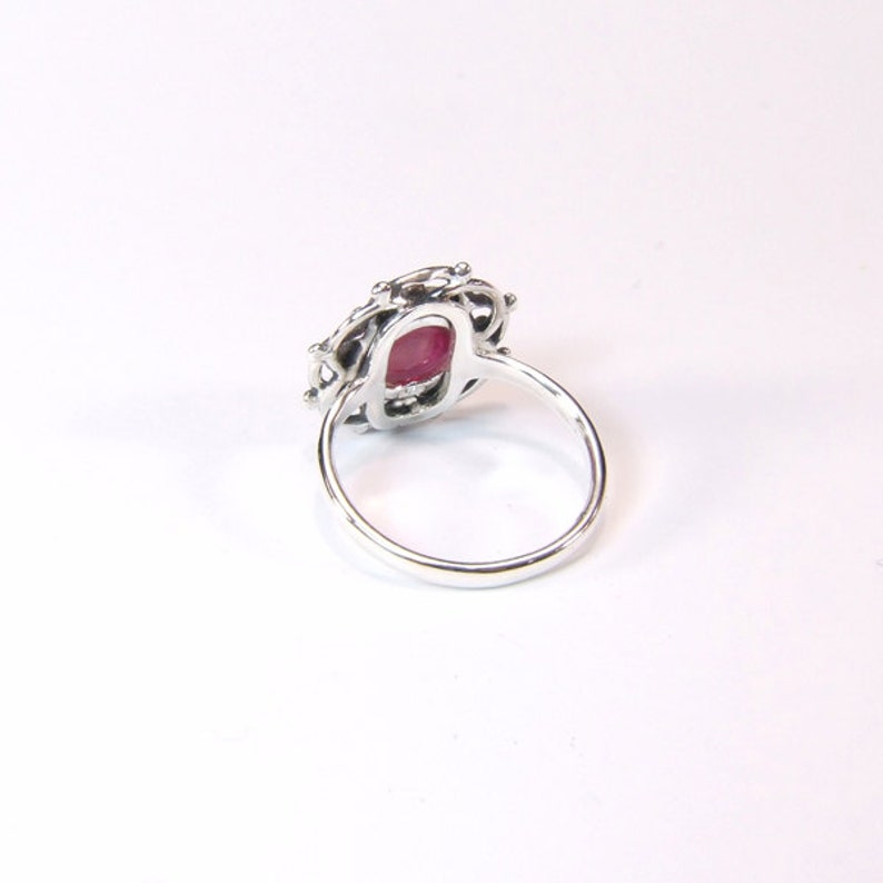 Puede incluir: Un anillo de plata con una piedra preciosa roja engastada en un delicado dise&ntilde;o de filigrana.
