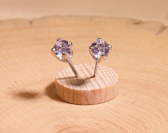 May include: A pair of silver stud earrings with small, round, light purple gemstones.