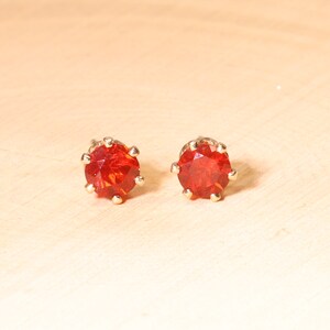 May include: A pair of gold stud earrings with red round gemstones.