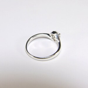 May include: A silver ring with a single clear stone set in a twisted band.