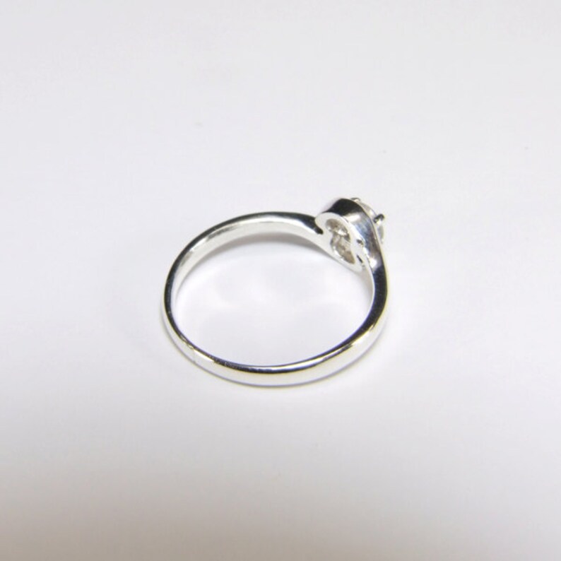 May include: A silver ring with a single clear stone set in a twisted band.