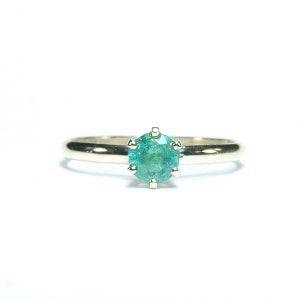 Pode incluir: Um anel de ouro com uma pedra preciosa redonda, verde-azulado claro. A pedra preciosa &eacute; engastada com seis garras. A banda do anel &eacute; de ouro polido simples. O anel est&aacute; centrado num fundo branco.