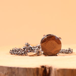 May include: A silver chain necklace with a round brown gemstone pendant.