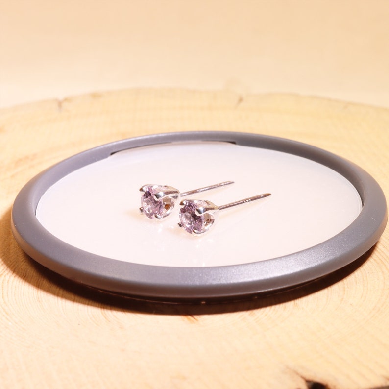 May include: A pair of silver stud earrings with small, round, light purple gemstones.