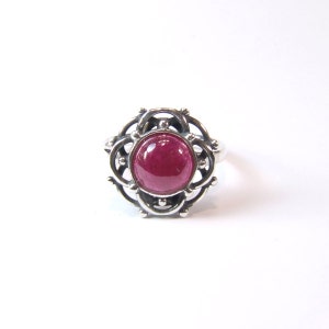 Puede incluir: Un anillo de plata con una piedra preciosa roja engastada en un dise&ntilde;o delicado e intrincado.