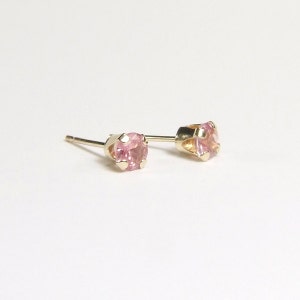 May include: A pair of gold stud earrings with pink gemstones.