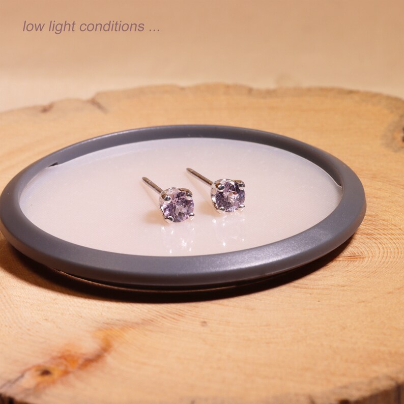 May include: A pair of silver stud earrings with small, round, light purple gemstones.
