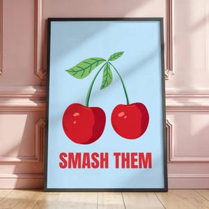 Peut inclure: Impression d'art encadrée avec deux cerises rouges vives et des tiges et feuilles vertes sur fond bleu clair. Le texte rouge vif "SMASH THEM" est en bas. L'œuvre est dans un cadre noir.