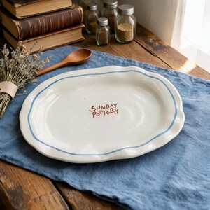 Hand-painted scalloped edge detail on a glossy white ceramic dessert plate.