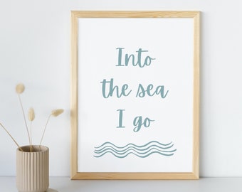 May include: A framed print with the text "Into the sea I go" in blue cursive font. The print has a white background and a wooden frame. There are three wavy lines in blue below the text.