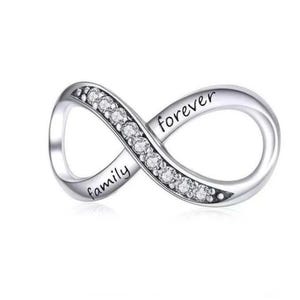 May include: A silver-toned infinity charm featuring a row of clear, sparkling stones along one side. The word family is engraved on the lower left curve, and the word forever is engraved on the upper right curve of the metallic infinity symbol.