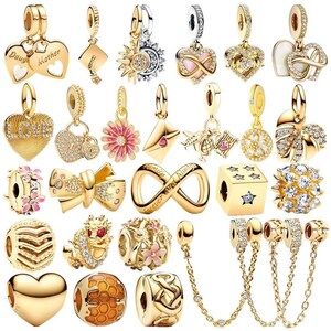 Könnte beinhalten: Eine Sammlung goldfarbener Metallanhänger für Armbänder in verschiedenen Formen, darunter Herzen, Blumen, ein Unendlichkeitssymbol mit dem Text Forever and Always, ein Würfel mit Sternen, ein Drache, eine Wabenkugel und Ketten mit Kristallen.