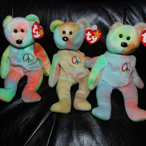 May include: A white ceramic mug with a black handle and the text "But First, Coffee" in a bold, black font. The mug is filled with a dark liquid, likely coffee, and sits on a light-colored surface.