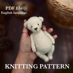 Puede incluir: Un pequeño oso de peluche blanquecino con rasgos faciales cosidos en negro se sostiene en una mano. El oso está hecho de un material texturizado. El texto en la parte superior dice "PDF file English language" y en la parte inferior "KNITTING PATTERN".
