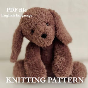 May include: A brown, plush dog toy with long, floppy ears and a black nose. The text "PDF file English language" is at the top, and "KNITTING PATTERN" is at the bottom. The toy is made of a soft, textured material.