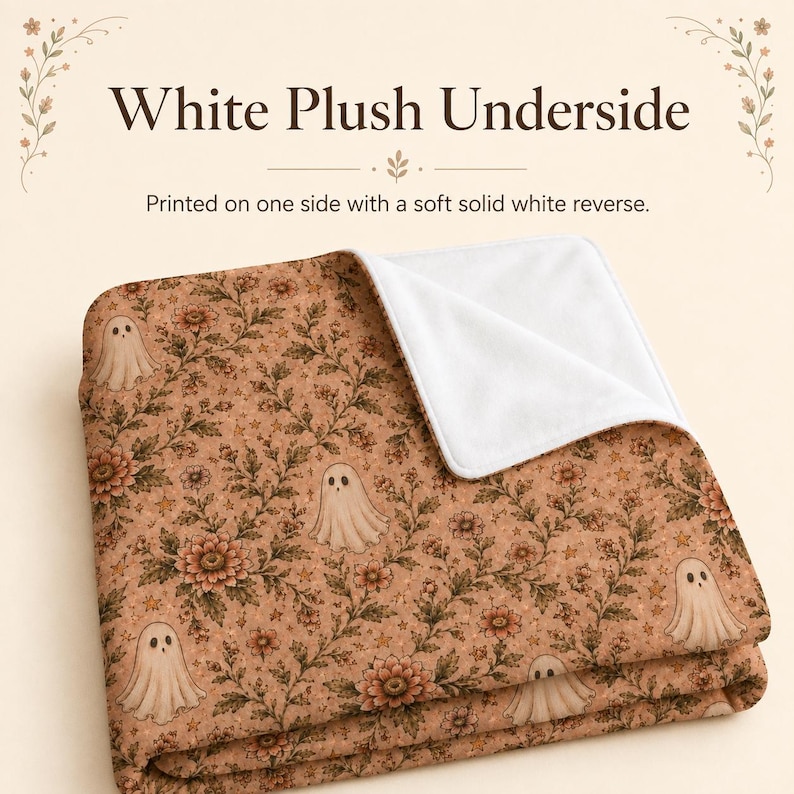 May include: A folded blanket featuring a tan background with a repeating pattern of small ghosts, flowers, and stars. The text White Plush Underside and Printed on one side with a soft solid white reverse is visible above the blanket.