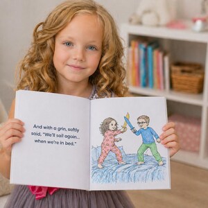 May include: A child holds a book open, revealing a colourful illustration of two children in pyjamas playing with swords. The text reads, "And with a grin, softly said, 'We'll sail again... when we're in bed.'" The girl smiles at the camera.