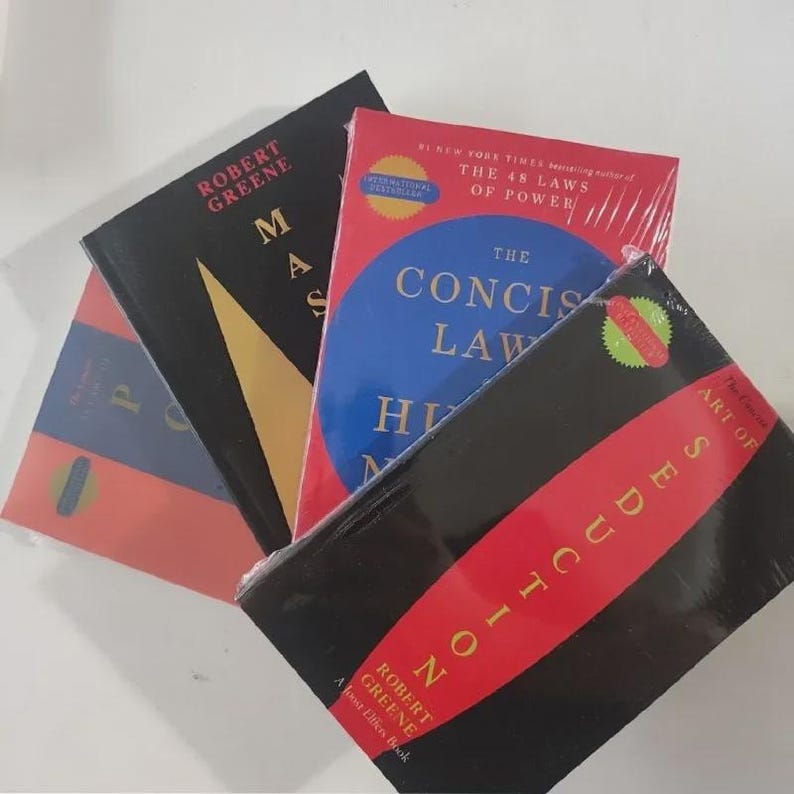 May include: A stack of hardcover books with various covers. Titles include "Mastery" and "The Concise Laws of Human Nature" by Robert Greene. The books are in different colors, including red, black, and blue, with text in white and yellow.