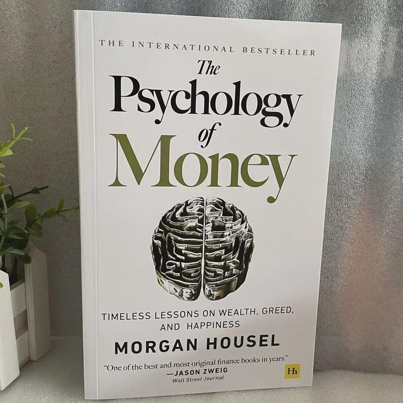 May include: A hardcover book titled "The Psychology of Money" with a white cover and green text. The cover features a brain-shaped illustration and the author's name, Morgan Housel. The book is described as a bestseller with lessons on wealth, greed, and happiness.