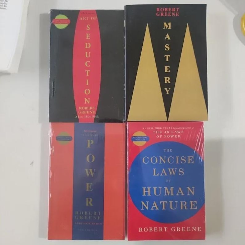 May include: Four hardcover books by Robert Greene are displayed. The books have various color schemes, including black, red, and blue. Titles include "Art of Seduction," "Mastery," "Power," and "The Concise Laws of Human Nature."