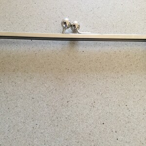 May include: A silver metal purse frame with two round metal clasps.