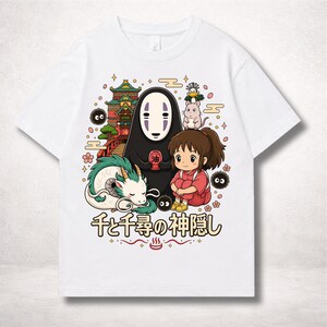 Op de afbeelding: Wit t-shirt met een kleurrijke afbeelding uit de animatiefilm Spirited Away. Het ontwerp toont personages als No-Face, Chihiro en Haku, samen met Japanse tekst. Het kunstwerk is omgeven door decoratieve elementen.