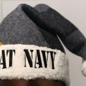 May include: A gray and white knit hat with a yellow patch and the words "Beat Navy" embroidered in black.