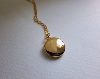 May include: A gold chain necklace with a round gold locket pendant.