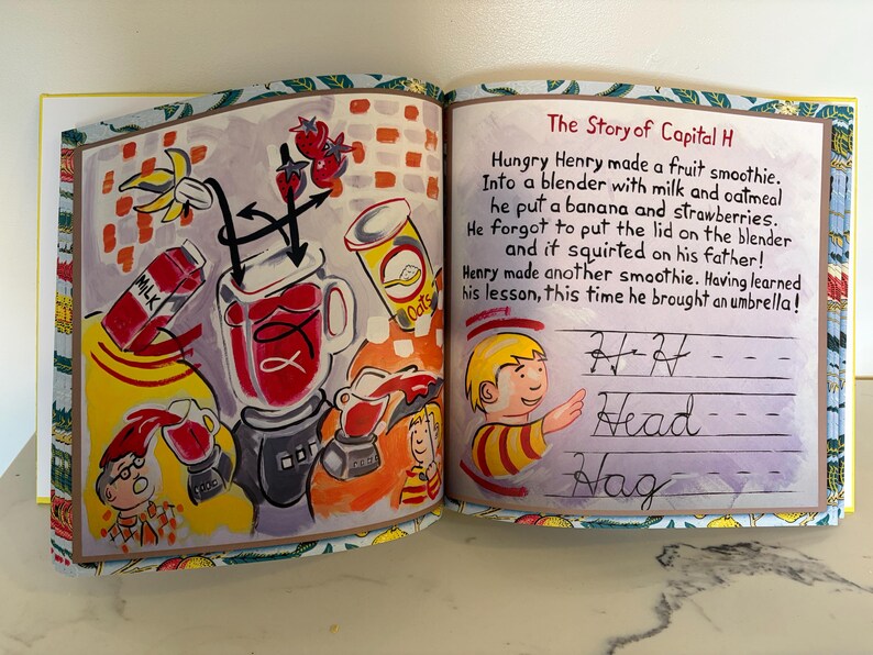 May include: An open children's book page featuring a colorful illustration of a blender, fruit, and milk, alongside the text The Story of Capital H. The right page shows a boy and cursive writing practice lines with the words H, Head, and Hag.