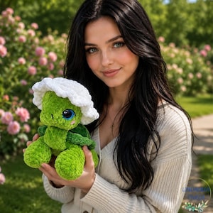 May include: A plush green turtle toy with a textured, soft surface, large dark eyes, and a white crocheted hat. The turtle has a rounded shell and small limbs, crafted from a fuzzy yarn material, held in place against a blurred outdoor garden background.