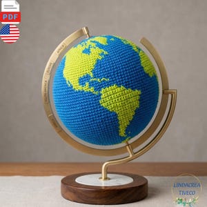 Peut inclure: Un globe composé d'une sphère crochetée aux océans bleus et aux continents vert lime. La sphère est montée sur un anneau méridien en métal doré et une base circulaire en bois avec une incrustation blanche effet marbre. L'anneau affiche du texte.