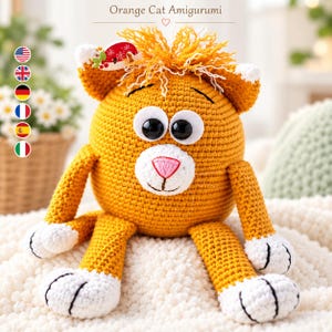 Op de afbeelding: Een oranje gehaakt amigurumi-speeltje in de vorm van een kat met een rond lichaam, grote zwarte ogen, een witte snuit en een roze geborduurde neus. De kat heeft witte pootjes, een pluk oranje garen op het hoofd en een rood-wit accessoire.