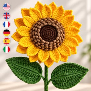 May include: A crochet sunflower featuring a dark brown textured center surrounded by bright yellow petals. The flower is attached to a green stem with two large, detailed green leaves extending from the sides, all crafted with yarn.