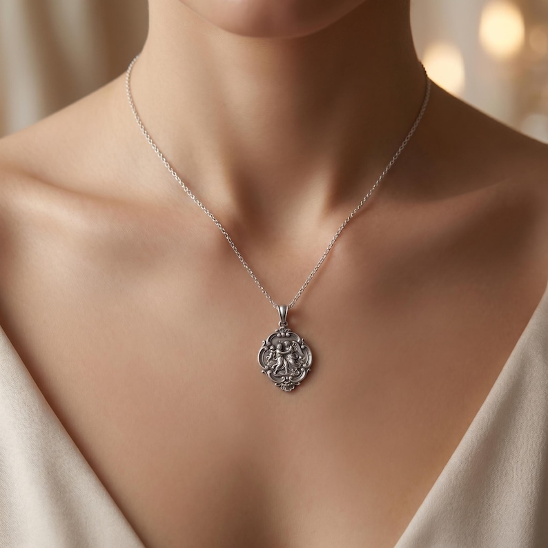 May include: A silver-toned necklace featuring a delicate chain and a small, ornate, oval-shaped pendant. The pendant displays a detailed, raised relief design of two figures in an embrace, framed by a decorative, scalloped border with intricate scrollwork.