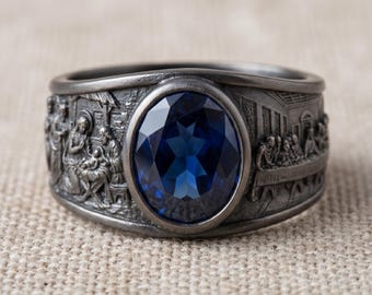Anillo de plata de ley con la Natividad bíblica y la Última Cena, con piedra de circonita cúbica azul.