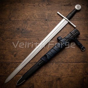 May include: A medieval sword with a silver blade and a black handle, alongside its blue leather sheath. The sword features a silver crossguard and a circular pommel. The sheath is black with blue leather detailing. The text "Velrit Forge" is visible.