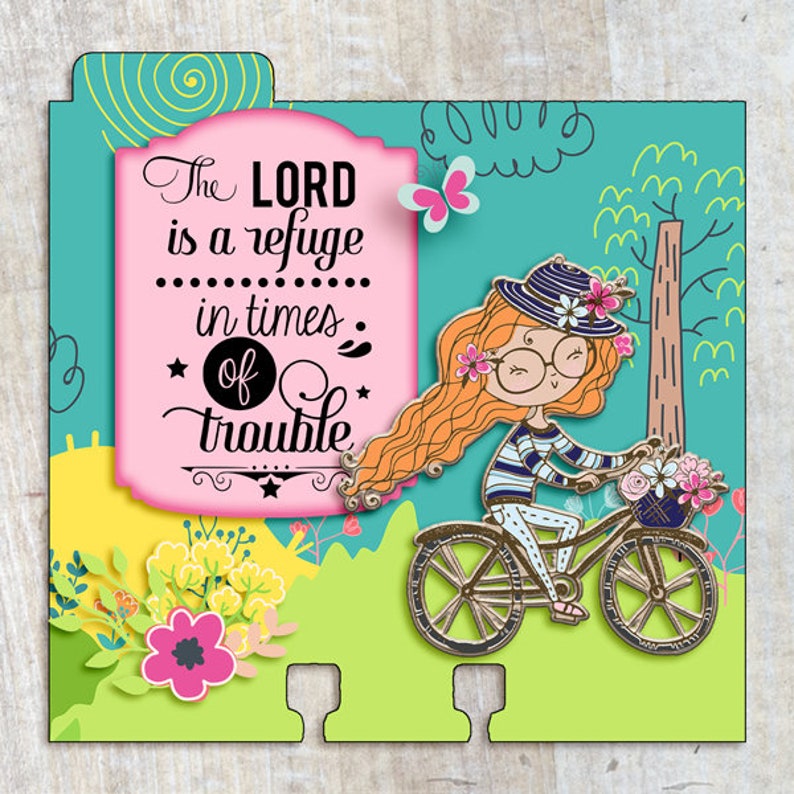 Puede incluir: Una tarjeta rosa y blanca con una cita sobre el Se&ntilde;or siendo un refugio en tiempos de problemas. La tarjeta presenta a una ni&ntilde;a de dibujos animados montando una bicicleta con flores en una cesta.