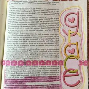 May include: A page from a book featuring the text Amazing Grace in floral-patterned letters at the top and the word Grace in pink and yellow vertical letters with heart accents on the right side, alongside pink decorative tape and text.
